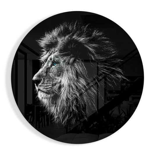 Black and white profile portrait of a lion with striking blue eye on circular glass wall art against dark background.