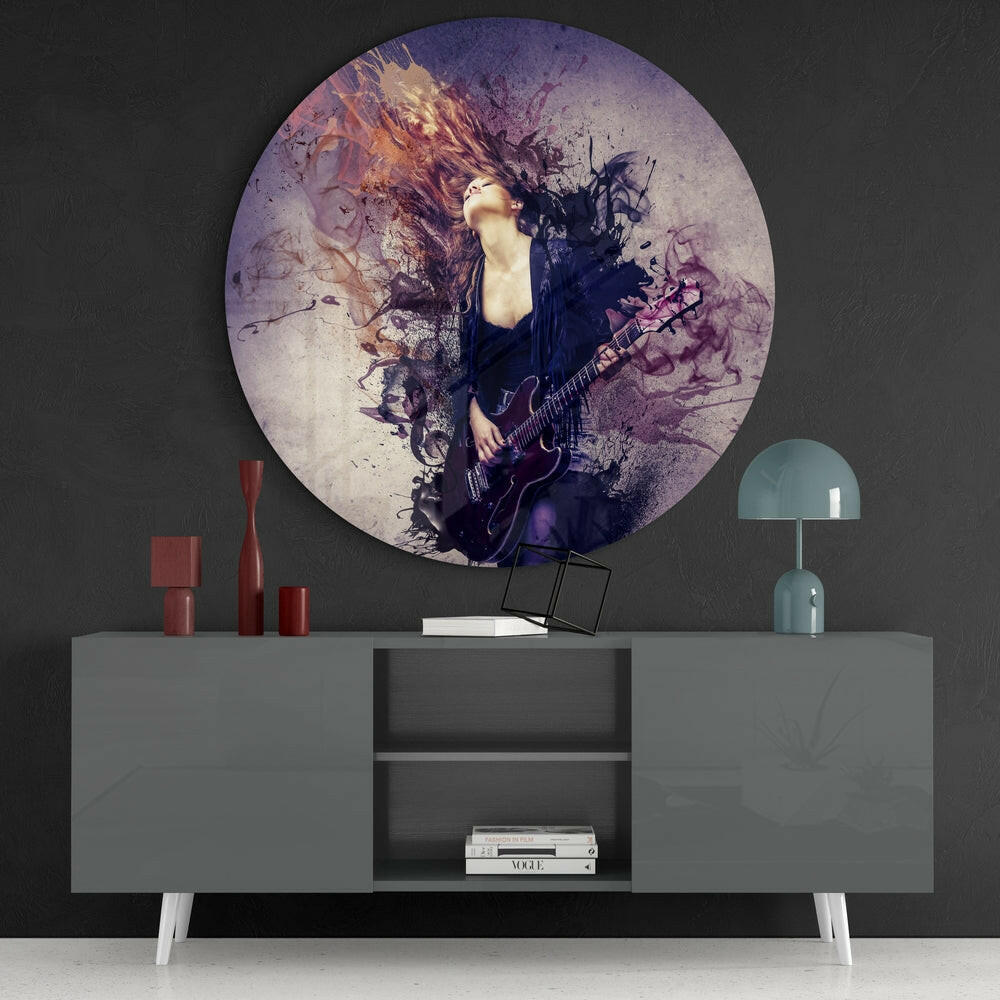 Circular glass wall art featuring a musician with electric guitar surrounded by purple and gold watercolor splatter effects, displayed above a gray console table.