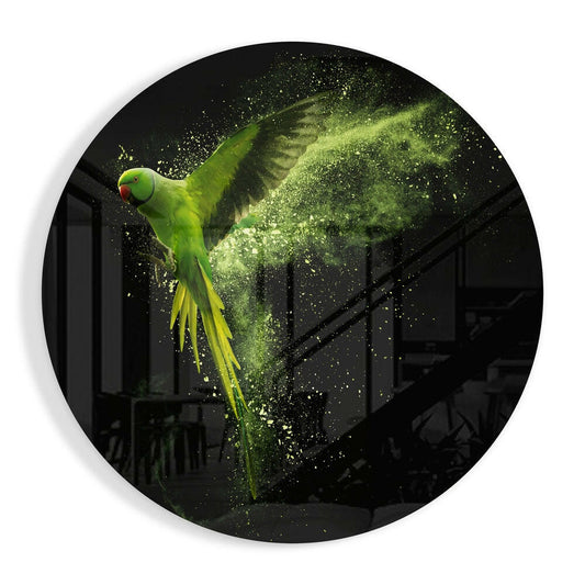 Bright green parakeet in flight with yellow tail feathers dispersing into glowing green powder dust against a dark interior background on circular glass wall art.
