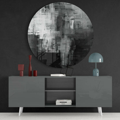 Abstract circular glass wall art with black, white and grey brushstroke patterns mounted above grey console table with red and blue accessories.