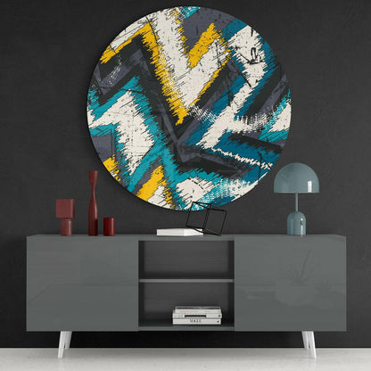 Circular glass wall art with turquoise, yellow, white and grey brushstroke pattern displayed above grey console table with red vases and teal lamp.