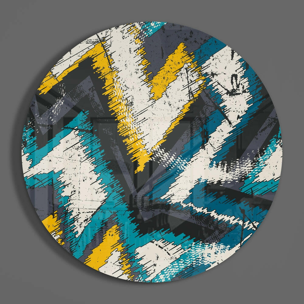 Circular glass wall art with diagonal zigzag stripes in teal, yellow, white, and charcoal with distressed texture, displayed against gray background.