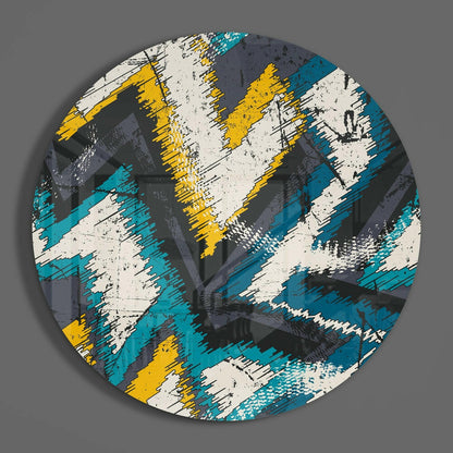 Circular glass wall art with diagonal zigzag stripes in teal, yellow, white, and charcoal with distressed texture, displayed against gray background.