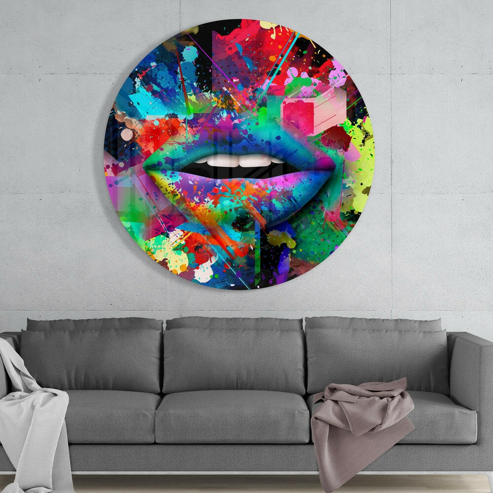 Colorful abstract lip glass wall art with vibrant paint splatter design hanging above gray sofa in modern living room.