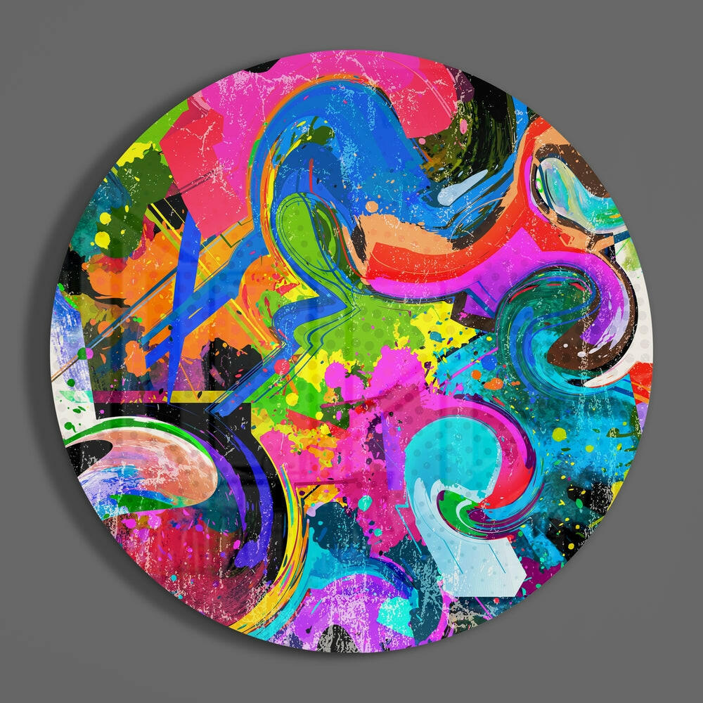 Circular glass wall art featuring vibrant, overlapping swirls in magenta, blue, lime green, orange, and cyan with black outlines and splatter effects on gray background.