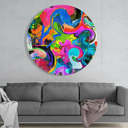Vibrant circular glass wall art with swirling blue, pink, green, and orange patterns hung above a gray sofa against white wall.