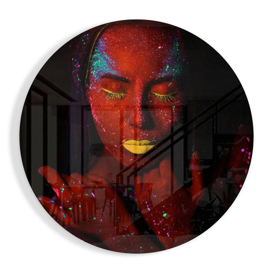 Circular glass art displaying a face in profile with closed eyes, bright red neon glow, golden eyelashes and lips, multicolored glitter accents, and architectural interior background overlay.