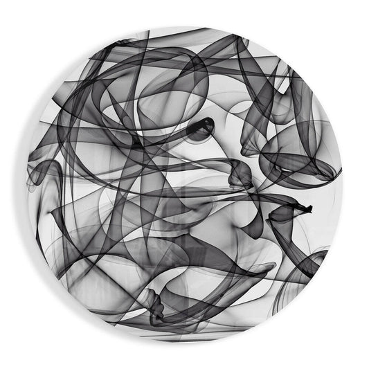 Overhead view of circular glass wall art with intricate black smoke-like wire loops and swirls on white background.
