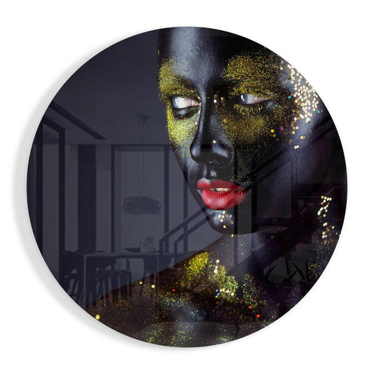 Circular glass wall art featuring a portrait with black skin, gold glitter eye makeup, red lips, and an interior room scene visible through the translucent design.