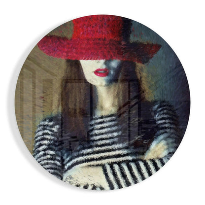 Circular glass wall art featuring a woman wearing a bold red hat and striped black-and-white gloves against a muted background.