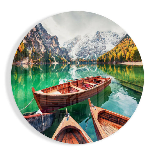 Three wooden rowboats moored on turquoise alpine lake with snow-capped mountains and golden larch trees reflected in water.