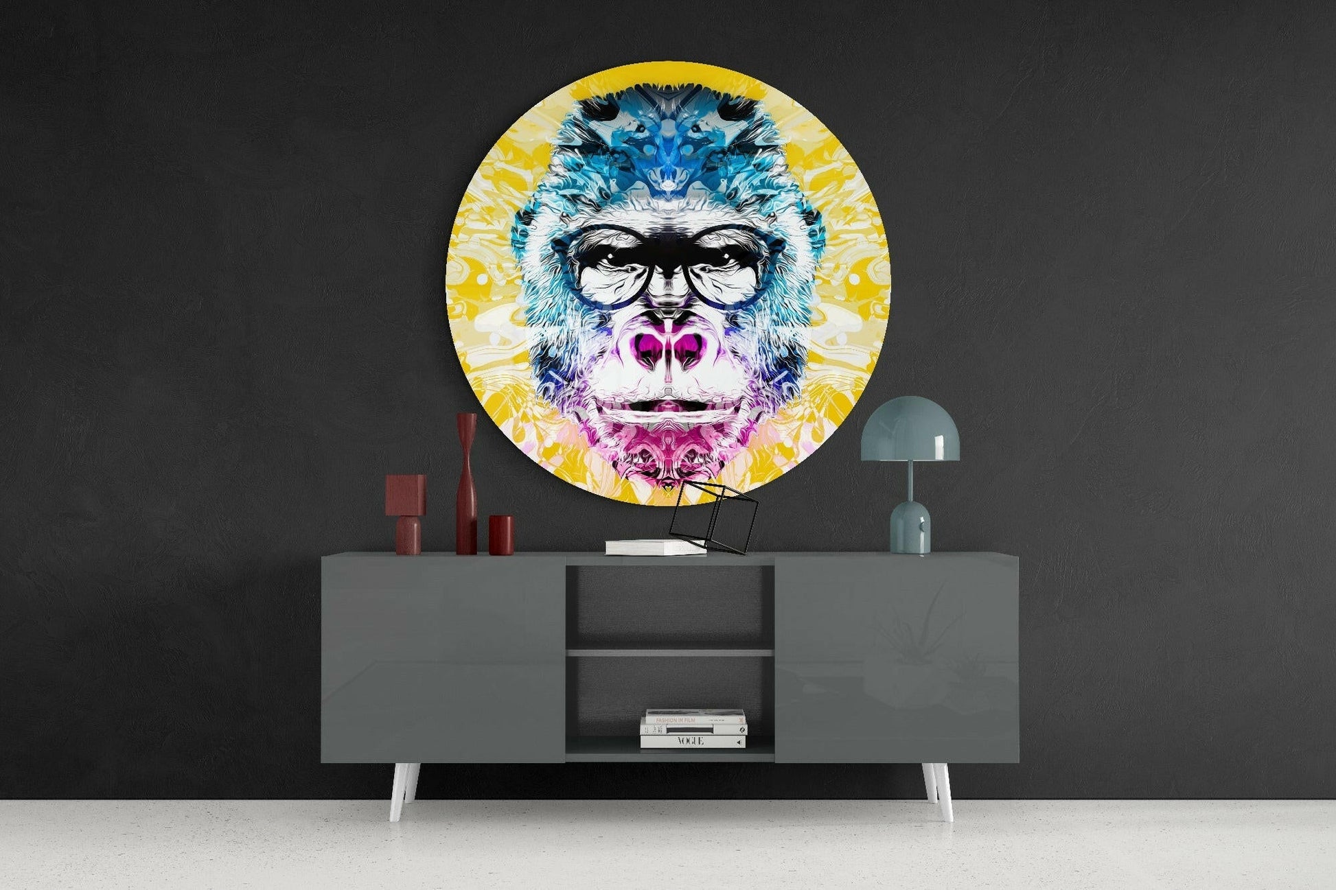 Colorful circular glass wall art depicting a stylized gorilla wearing glasses displayed above a gray modern sideboard in a dark interior setting.