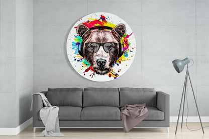 Circular glass wall art depicting a bear wearing headphones surrounded by colorful paint splashes, displayed above a gray sofa in a minimalist interior.