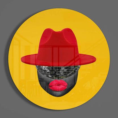 Red hat glass wall art featuring a stylized face with disco ball eyes and red lips against bright yellow circular background.
