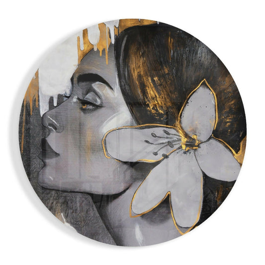 Circular glass wall art featuring a woman's profile in grayscale with gold drip details and a white lily with gold outline against a dark background.