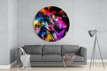 Vibrant circular glass wall art depicting colorful lion head in magenta, blue, and gold tones displayed above gray sofa in modern living room.