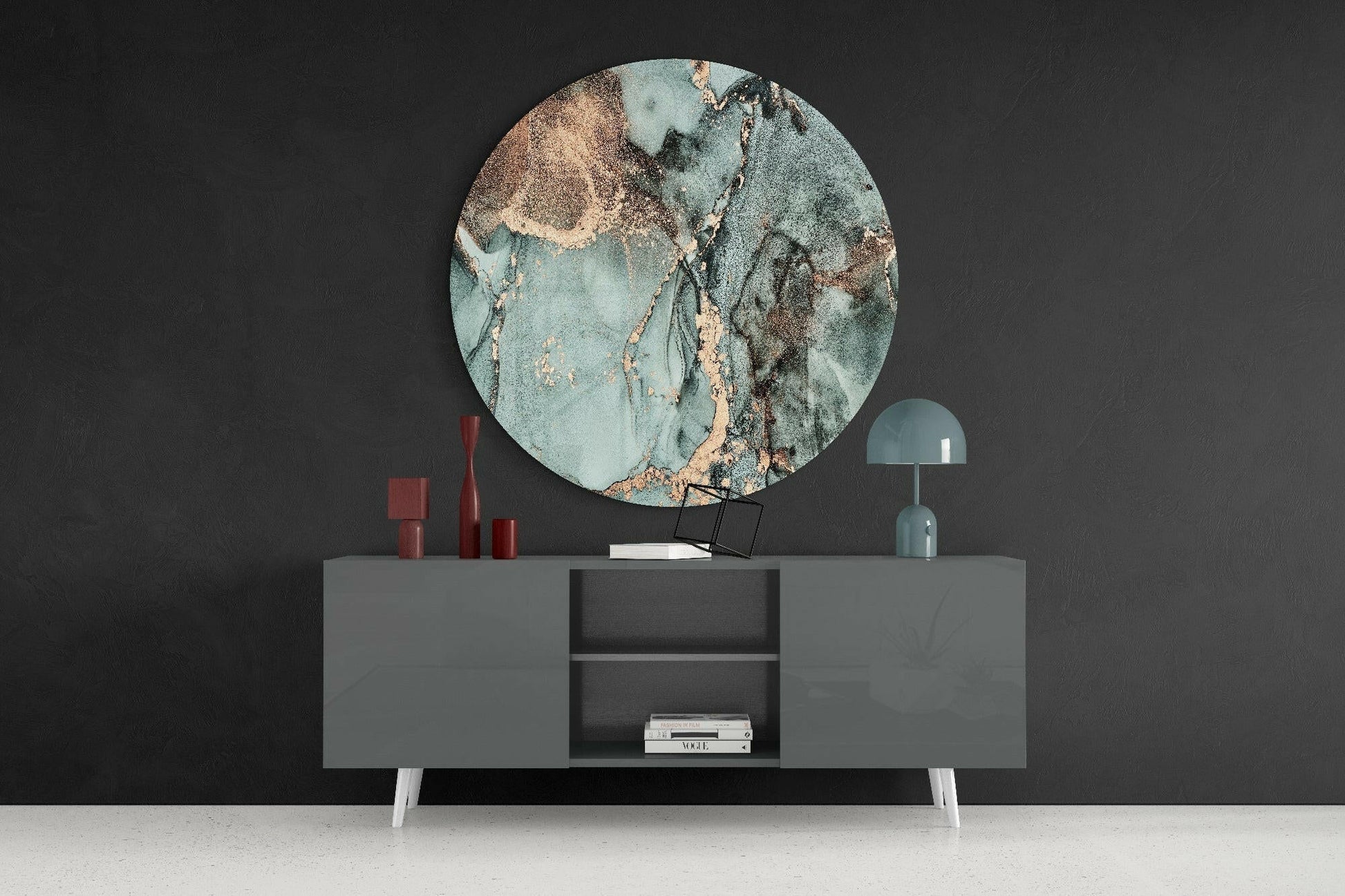 Round turquoise marble glass wall art displayed above gray sideboard with red candles and teal lamp against dark wall.