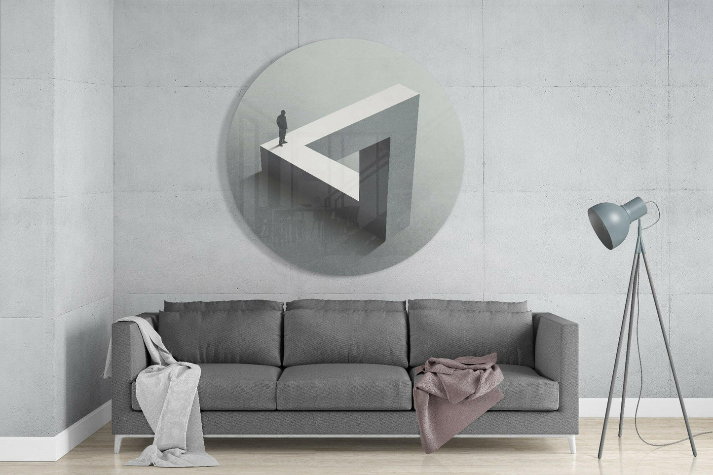 Circular glass wall art depicting an isometric labyrinth with a figure standing on white geometric platform, mounted above gray sofa in minimalist interior.