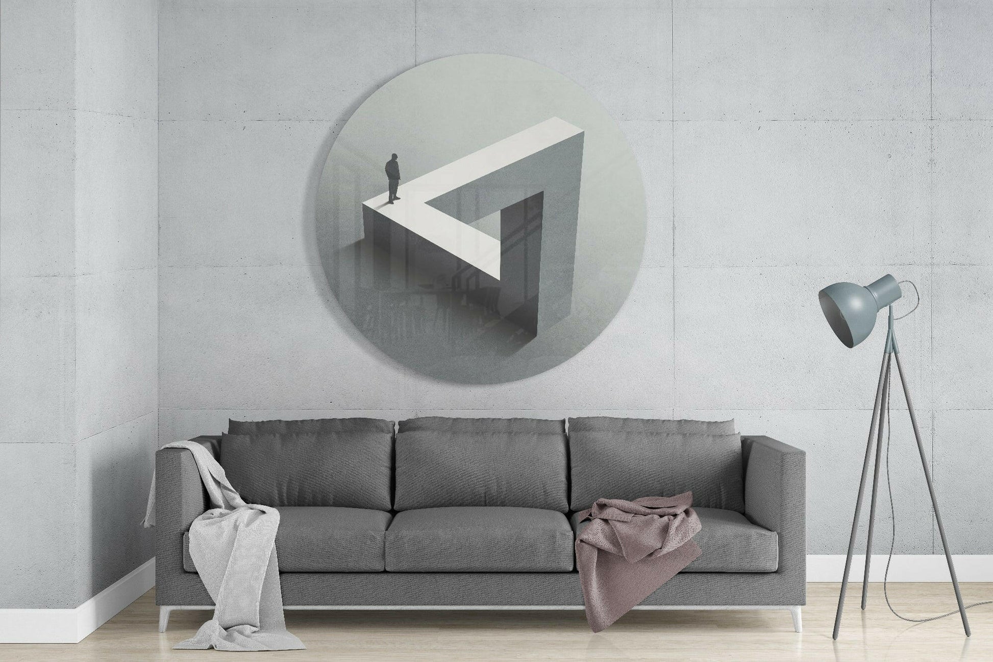 Circular glass wall art depicting an isometric labyrinth with a figure standing on white geometric platform, mounted above gray sofa in minimalist interior.