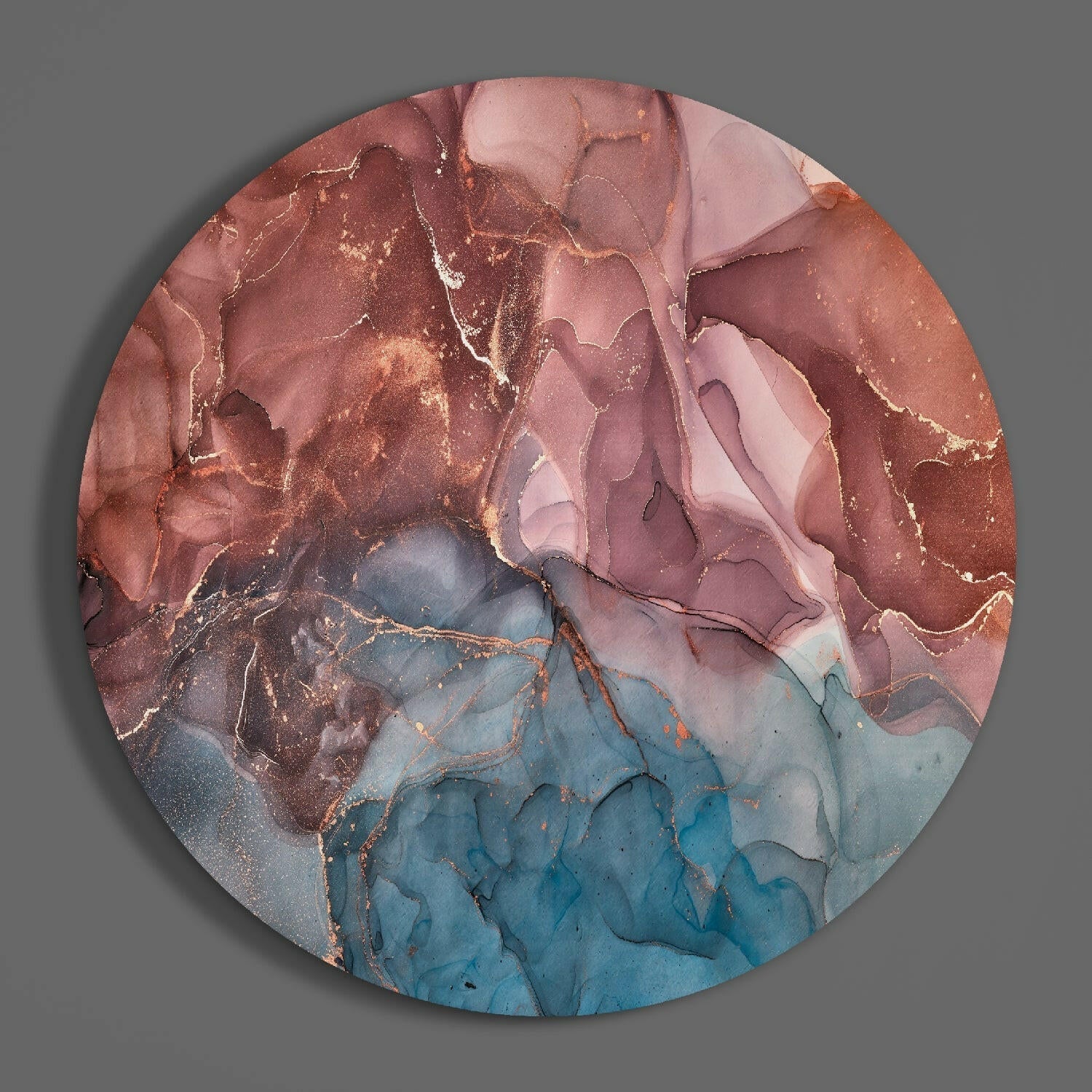 Circular glass wall art with flowing marbled patterns in terracotta, pink, and blue tones with gold accents, viewed from front.