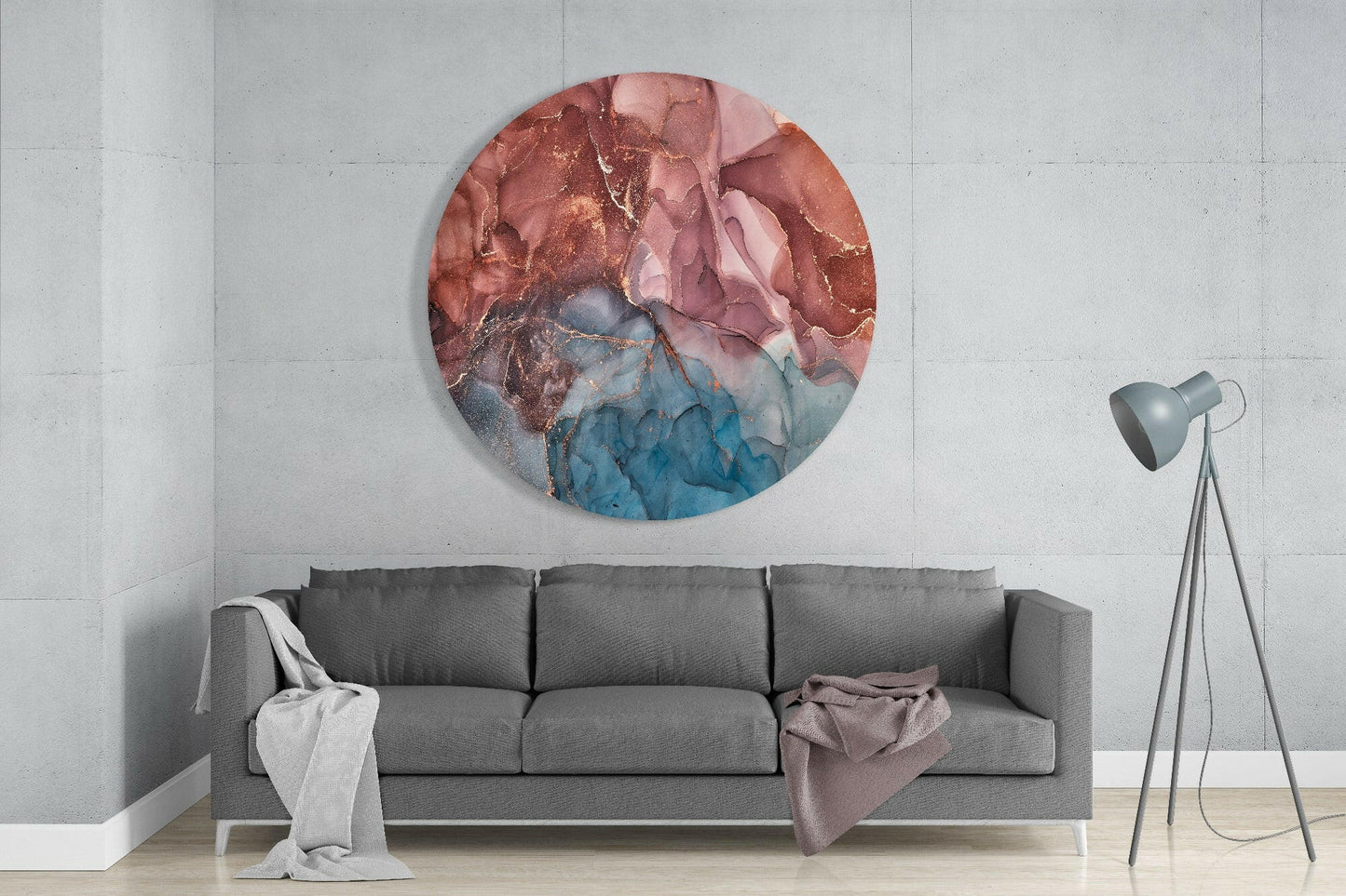 Round glass wall art with red, pink, and blue marbled abstract design, displayed above gray sofa in modern interior.