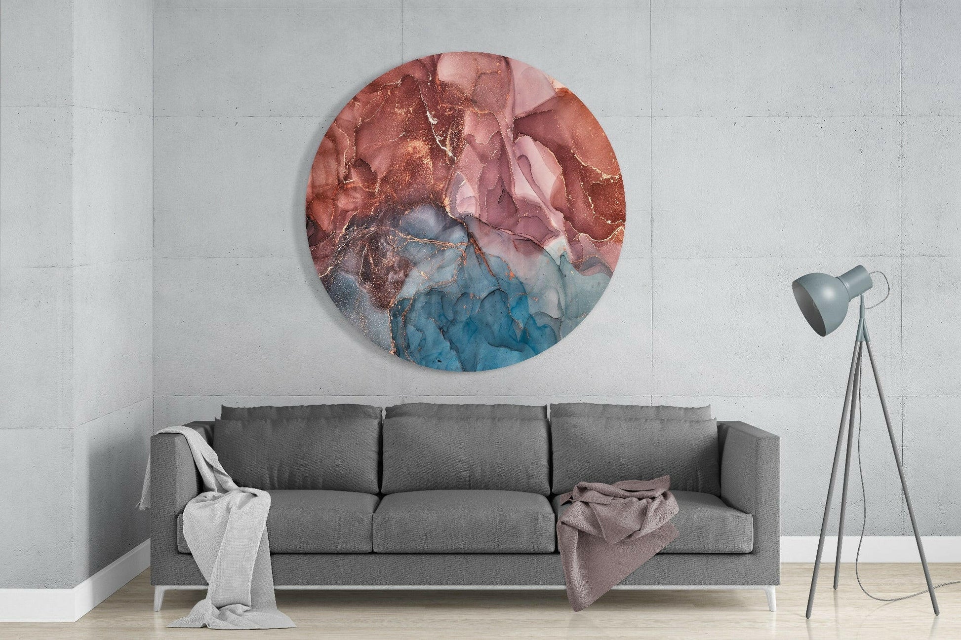 Round glass wall art with red, pink, and blue marbled abstract design, displayed above gray sofa in modern interior.