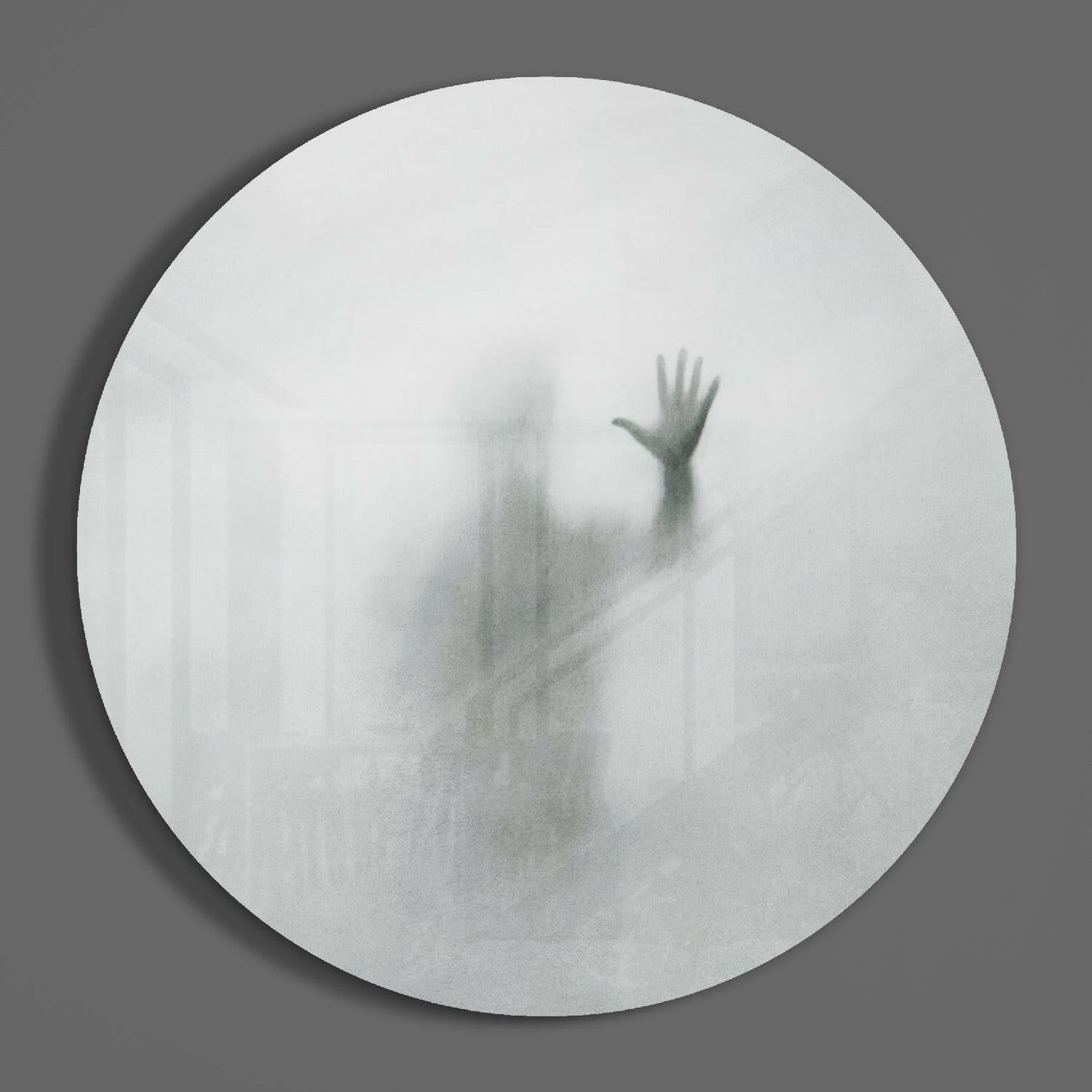 Blurred silhouette of a figure with raised hand visible through frosted white circular glass panel against gray background.