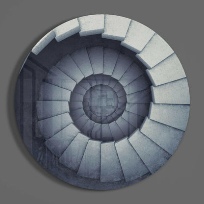 Overhead view of a spiral staircase with white stone steps descending into shadow, rendered in glass wall art.