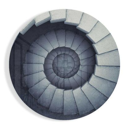 Overhead view of a spiral staircase with concrete steps descending into darkness, rendered in grayscale tones.