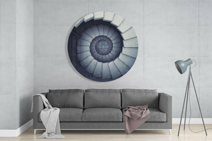 Circular stair glass wall art with concentric gradient design mounted above gray sofa in modern living room interior.
