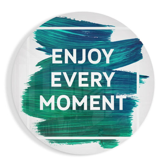 Circular glass wall art with white background and teal brushstroke design displaying "ENJOY EVERY MOMENT" in white text.