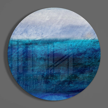Circular glass wall art displaying layered ocean and sky gradient, transitioning from white clouds at top through turquoise and deep blue water tones below.
