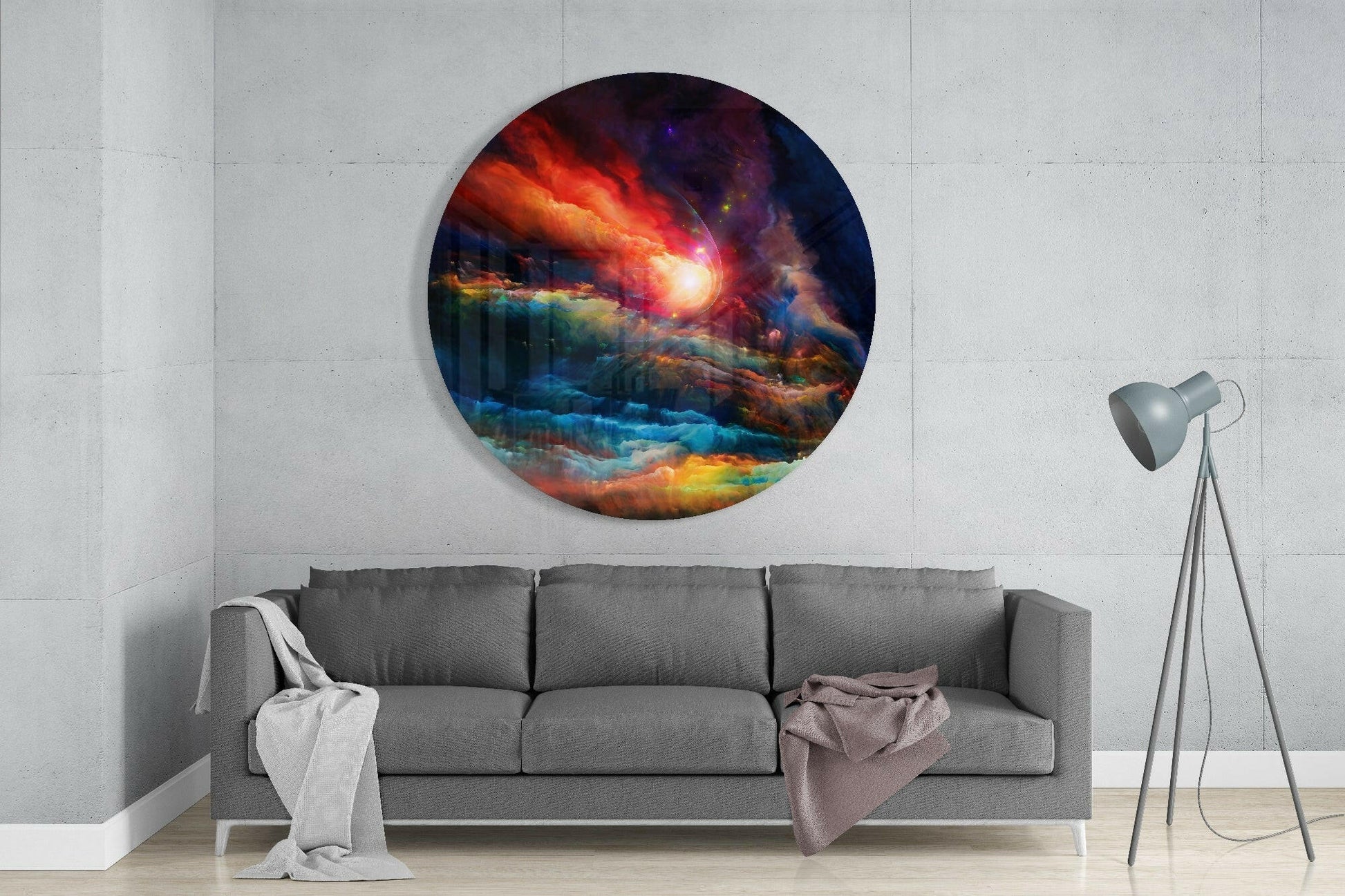 Circular glass wall art depicting a cosmic landscape with red, orange, blue, and purple nebula clouds, mounted above a gray sofa in a minimalist interior.