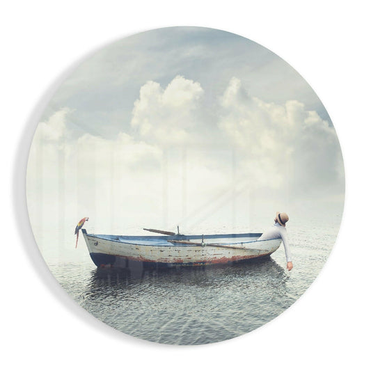 Circular glass wall art displaying a weathered fishing boat in shallow turquoise water beneath cloudy sky.