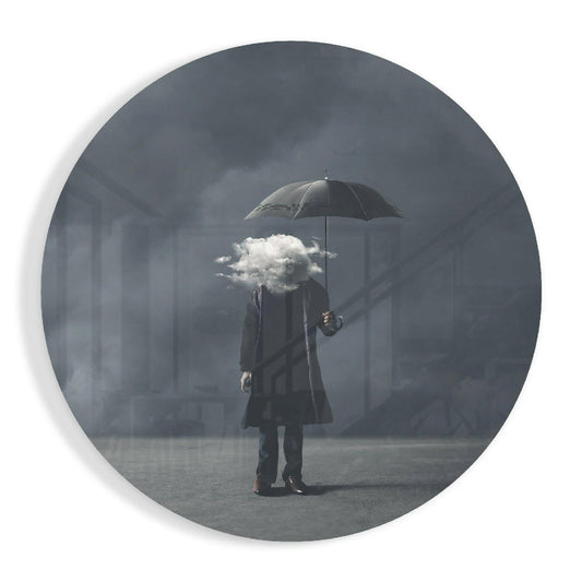 A person in dark clothing holds a black umbrella shielding a white cloud against a gray misty urban background, displayed on circular glass wall art.