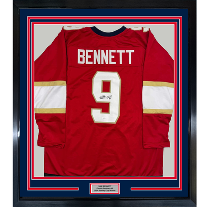 Red Florida Panthers hockey jersey number 9 signed by Sam Bennett, displayed flat in a framed mount with white and gold stripes.