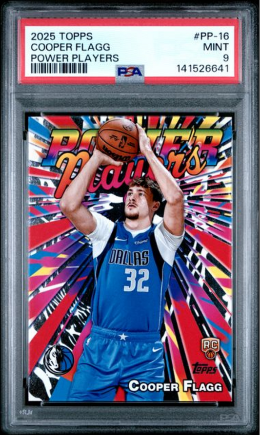 PSA-graded card in clear plastic case showing Cooper Flagg in Dallas Mavericks blue jersey shooting basketball against colorful pink and multicolored burst background.