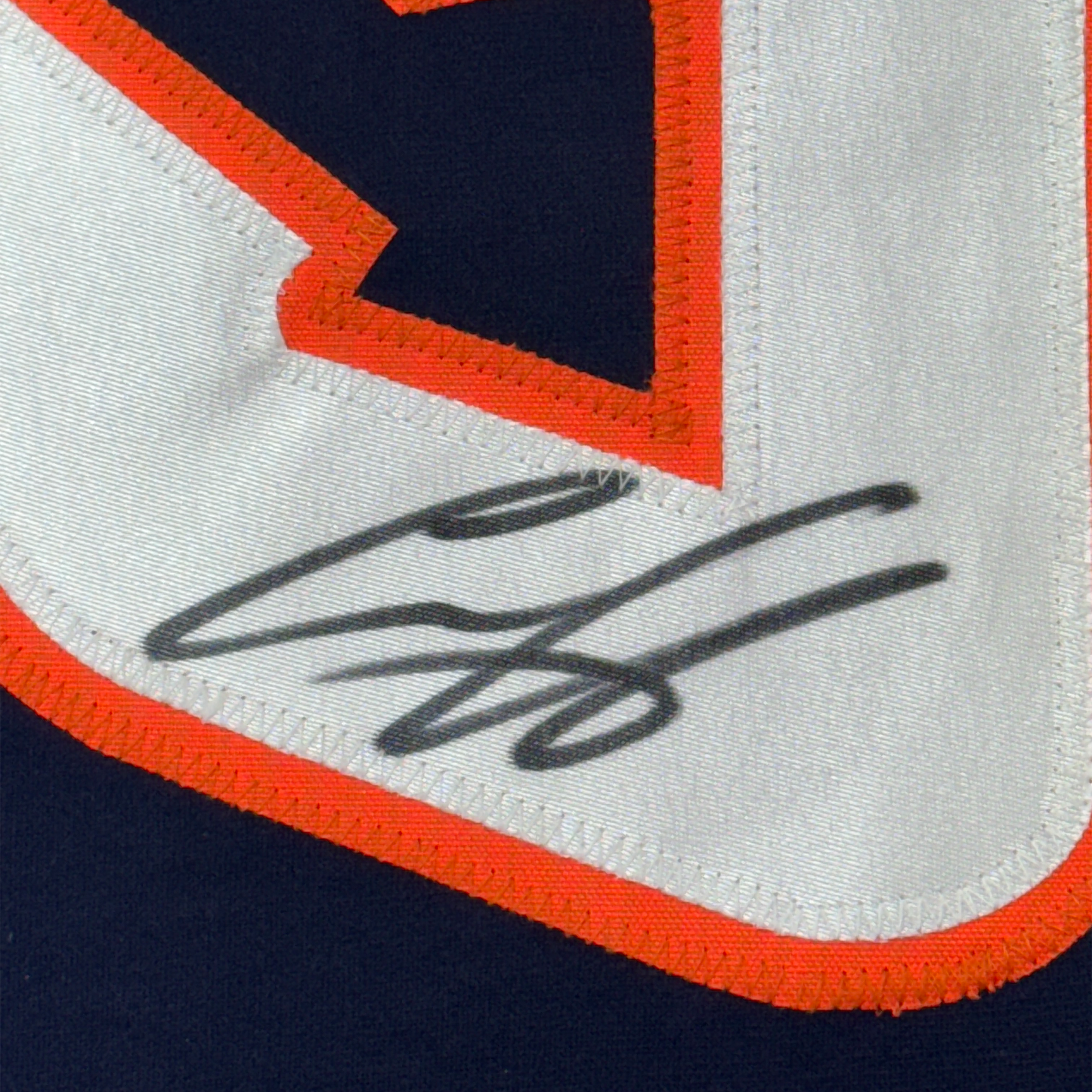 Close-up of autographed signature in black ink on white fabric with orange and navy blue trim detail.