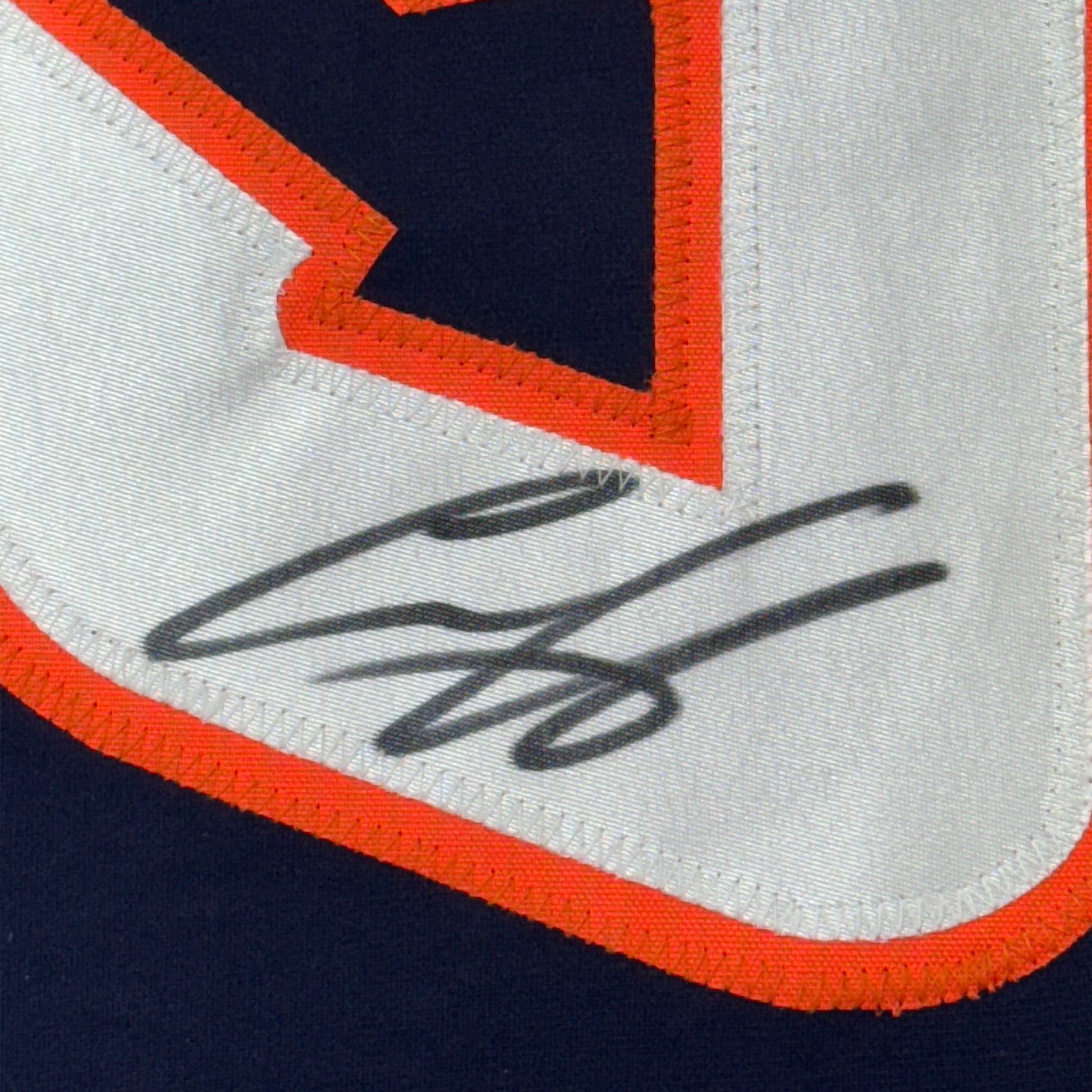 Close-up of autographed signature in black ink on white fabric with orange and navy blue trim detail.