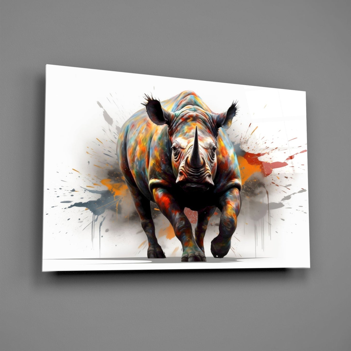 Colorful glass wall art displaying a frontal view of a rhinoceros with vibrant paint splatter effects in orange, yellow, and red tones against white background.