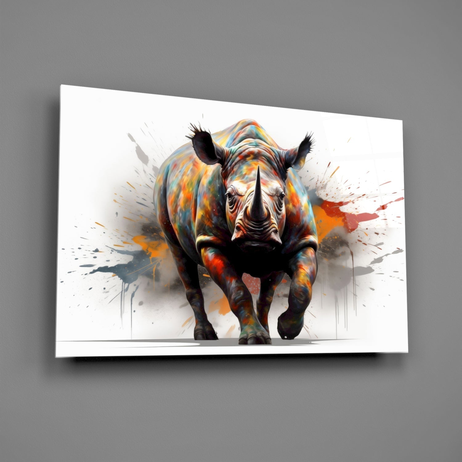 Colorful glass wall art displaying a frontal view of a rhinoceros with vibrant paint splatter effects in orange, yellow, and red tones against white background.