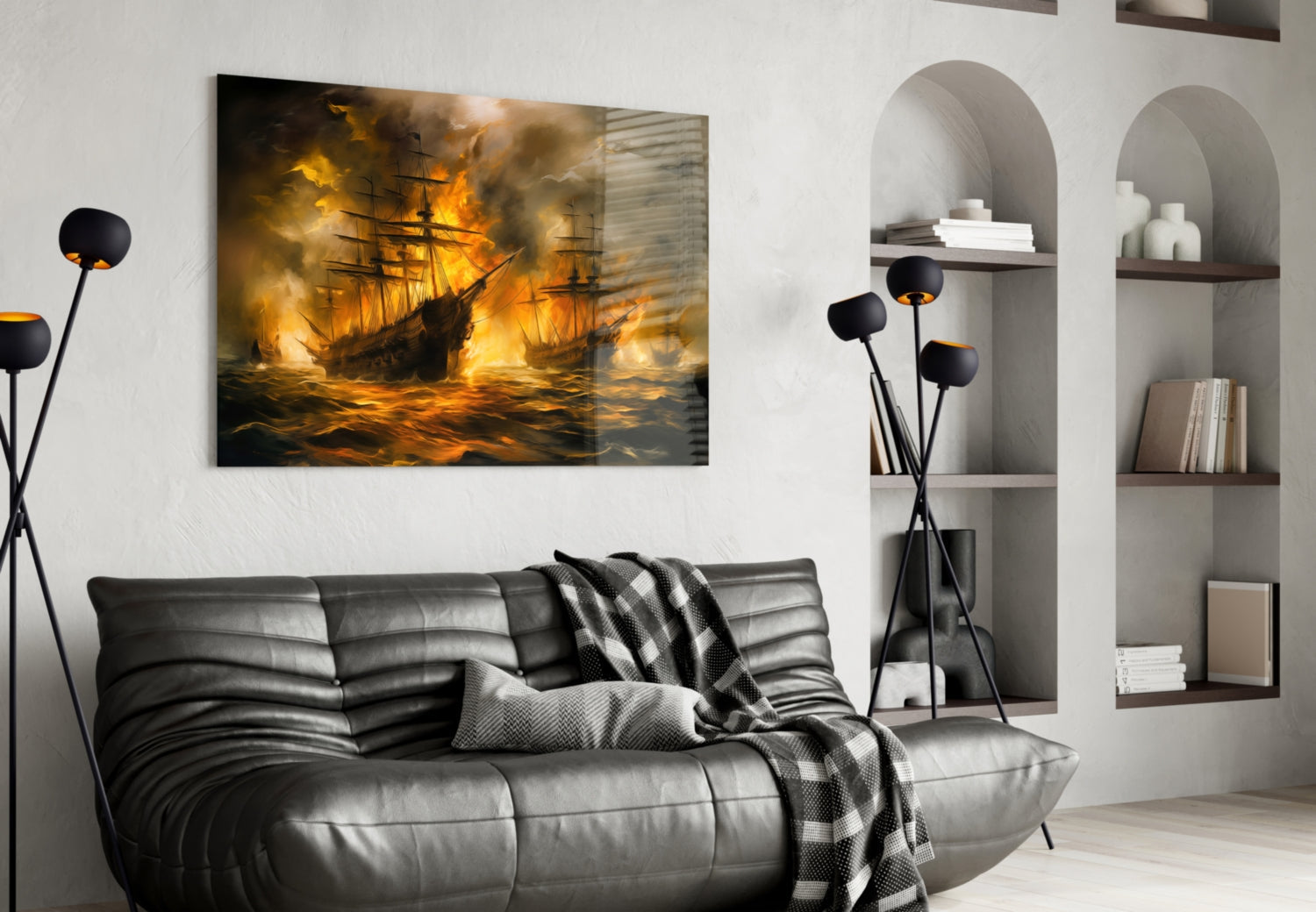 Glass wall art depicting burning sailing ships in golden flames hangs above a gray leather sofa in a modern living room.
