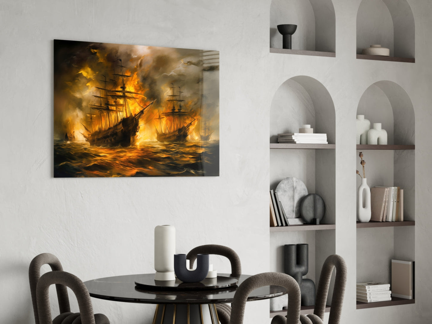 Burning sailing ships glass art displayed above a round black dining table in a modern interior with white shelving.