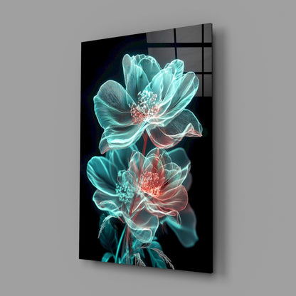 Angled view of glass wall art displaying two neon turquoise and coral glowing flowers against black background.