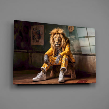 A lion wearing a yellow jacket and white sneakers sits on a wooden stool in a rustic room, displayed as glass wall art.