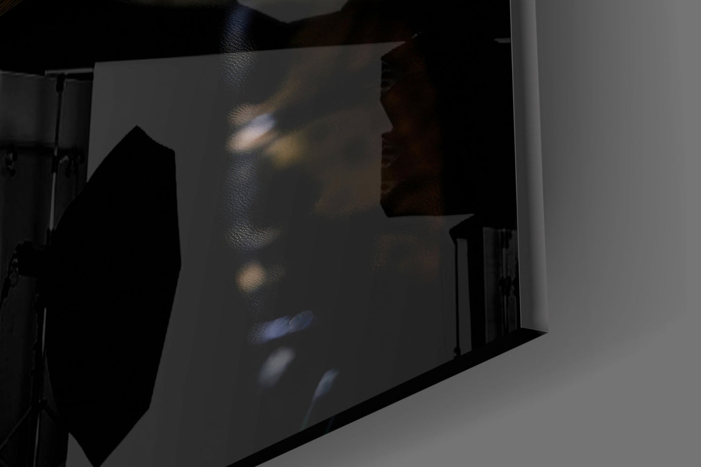 Glass wall art displaying shadowy swamp creature eyes with blue and amber tones, photographed at an angle showing translucent glass surface and black frame edge.
