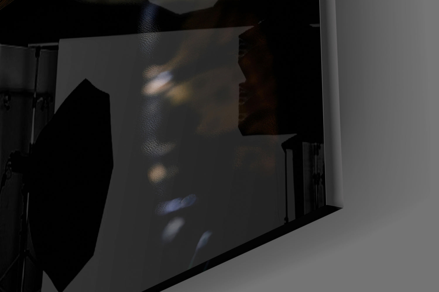 Glass wall art displaying shadowy swamp creature eyes with blue and amber tones, photographed at an angle showing translucent glass surface and black frame edge.