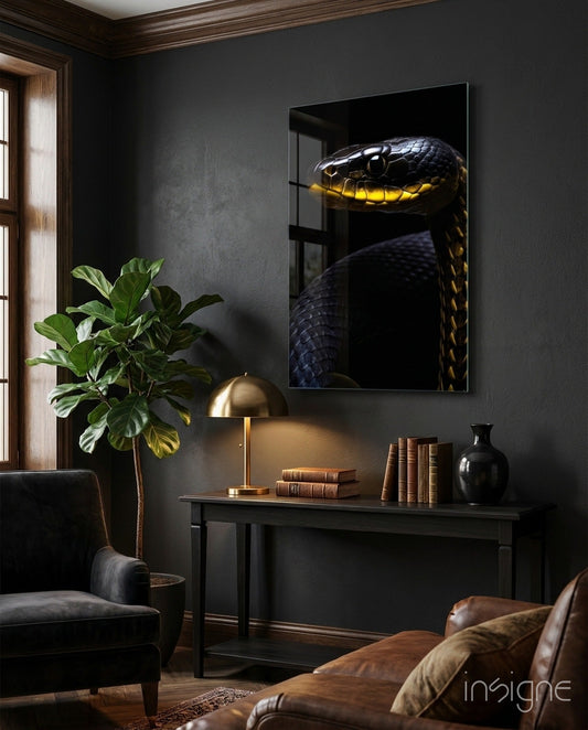 Black and yellow snake glass wall art displayed above a dark console table in a moody interior setting with brass lamp and books.