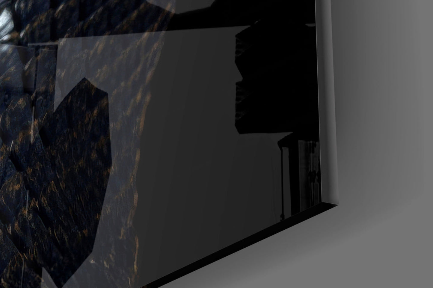 Close-up side view of black glass wall art with golden eye detail mounted on white wall surface.