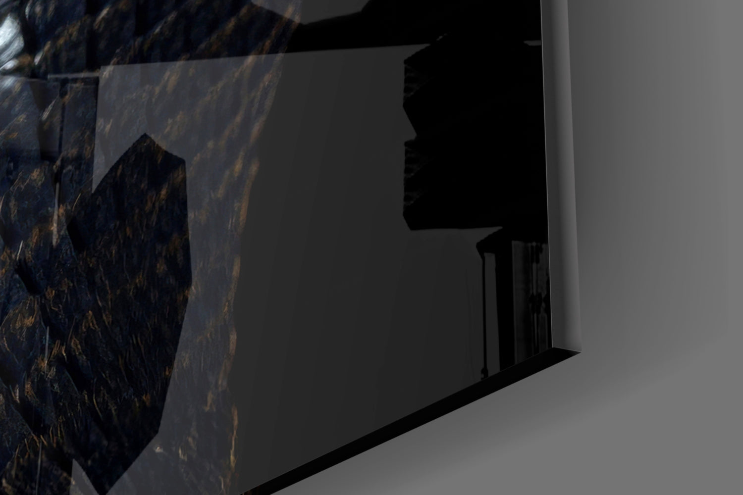 Close-up side view of black glass wall art with golden eye detail mounted on white wall surface.